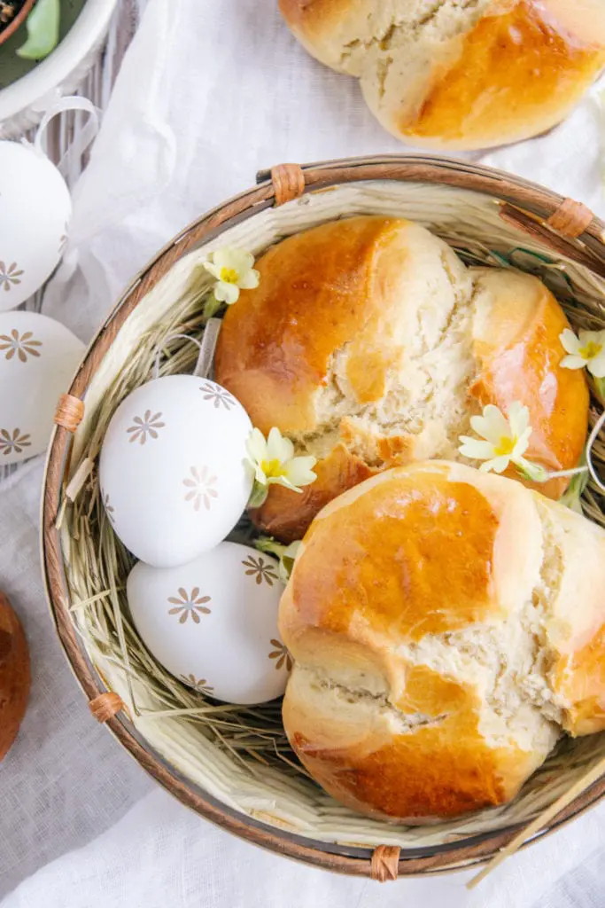 Zwei Dinkel-Osterpinzen ohne Zucker in einem Osternest mit zwei Ostereiern und Schlüsselblumen. Aufnahme von oben.