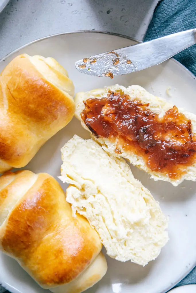 Aufgeschnittenes und auf einer Seite mit Marmelade bestrichenes Milchbrötchen von oben aus der Nähe fotografiert