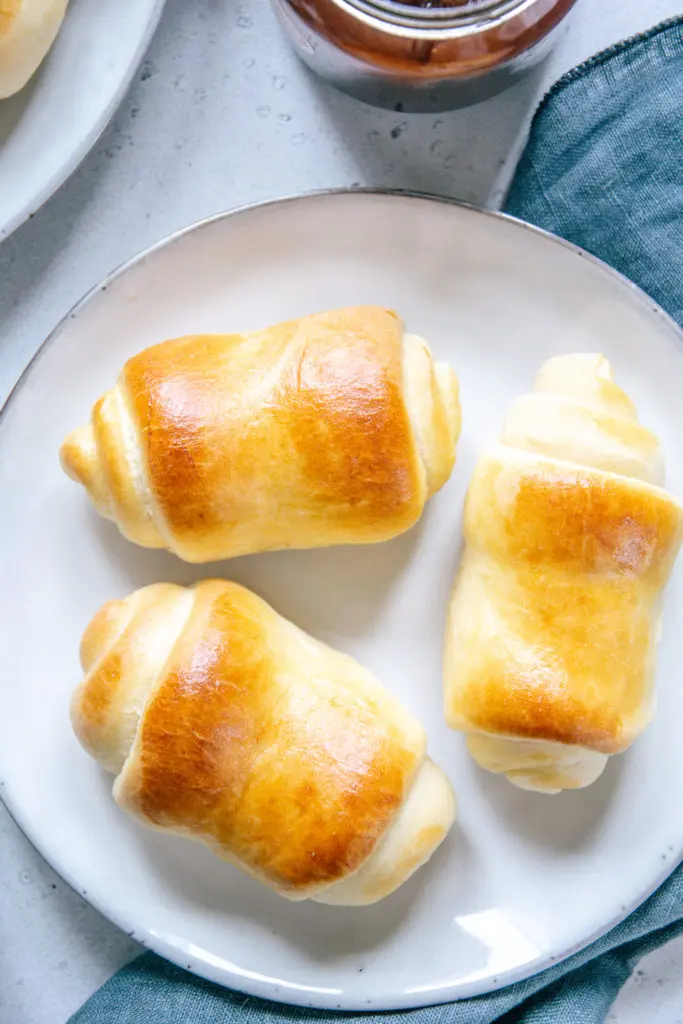 Drei Milchbrötchen auf einem graublauen Teller von oben fotografiert