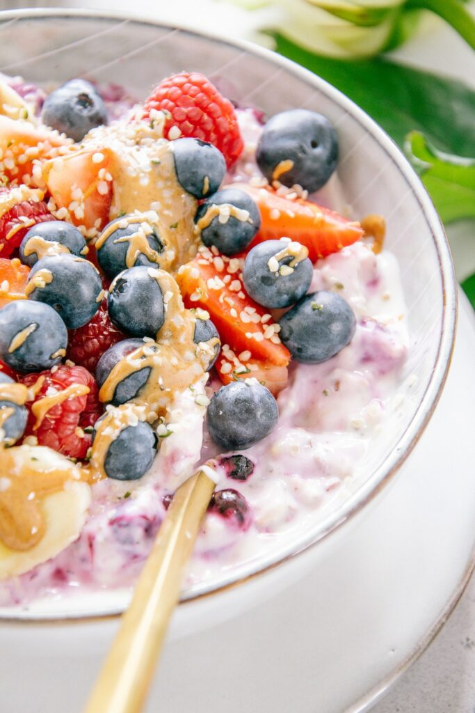 Nahaufnahme von Beeren-Bananen-Müsli im 45-Grad-Winkel. Die Cremigkeit ist deutlich erkennbar und das Mandelmus fließt wunderbar über die Beeren.