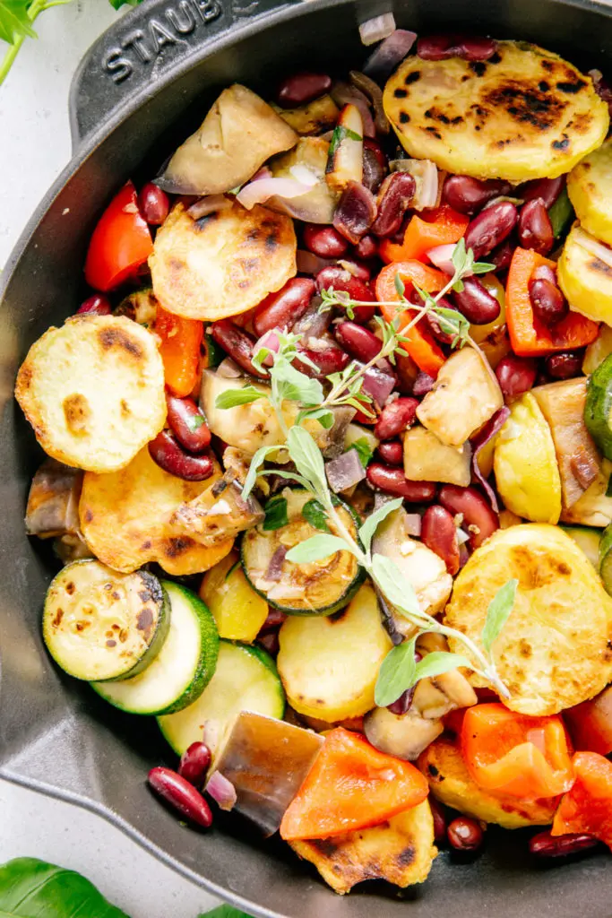 Nahaufnahme von Mediterraner Bratkartoffel-Gemüsepfanne von oben. Kartoffeln, Zucchini, Melanzani, Paprika und Kidneybohnen sind deutlich erkennbar.