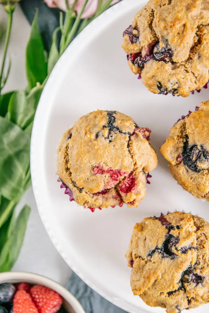 Nahaufnahme von veganen zuckerfreien Beerenmuffins von oben auf einer weißen Tortenplatte