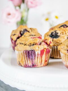 Vegane zuckerfreie Beerenmuffins auf Augenhöhe auf einer weißen Tortenplatte fotografiert