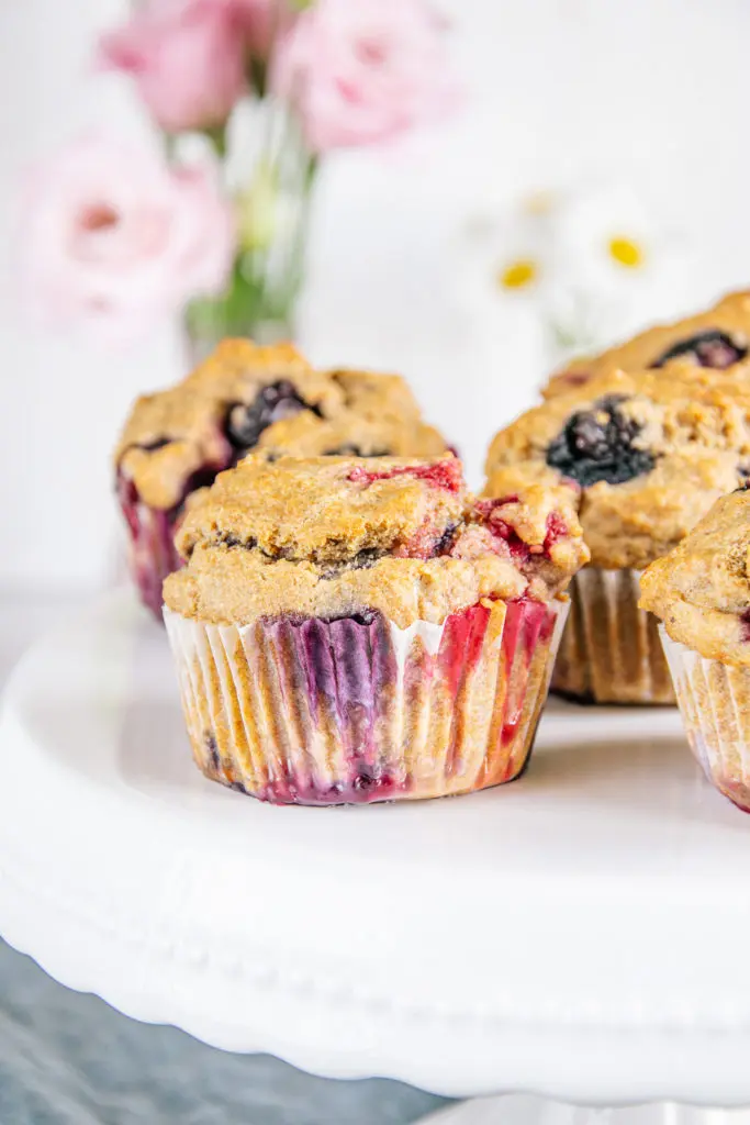 Vegane zuckerfreie Beerenmuffins auf Augenhöhe auf einer weißen Tortenplatte fotografiert