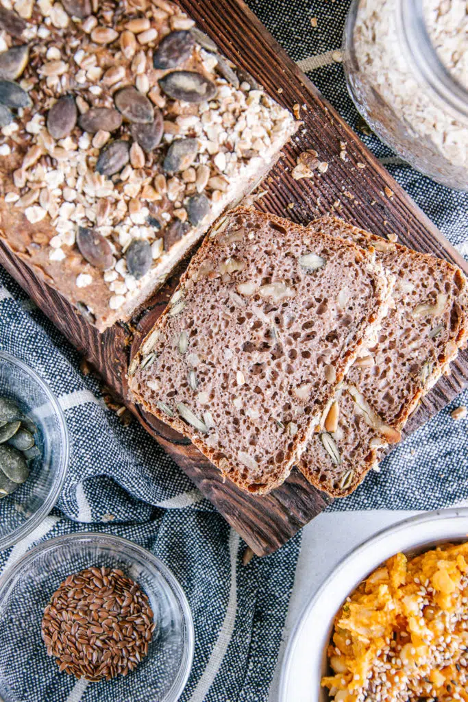 Zwei Scheiben Vollkorn-Walnussbrot aus der Vogelperspektive auf einem rustikalen Holzbrett direkt vom Brot abgeschnitten.