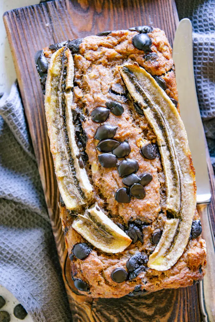 Nahaufnahme aus der Vogelperspektive von Chocolate Chip Bananenbrot mit einer halbierten Banane und Chocolate Chips als Topping