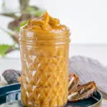 Selbstgemachte Dattelcreme in einem Glas im 45-Grad-Winkel fotografiert. Die hellbraune Creme ragt oben aus dem Glas heraus und bildet eine Spitze.