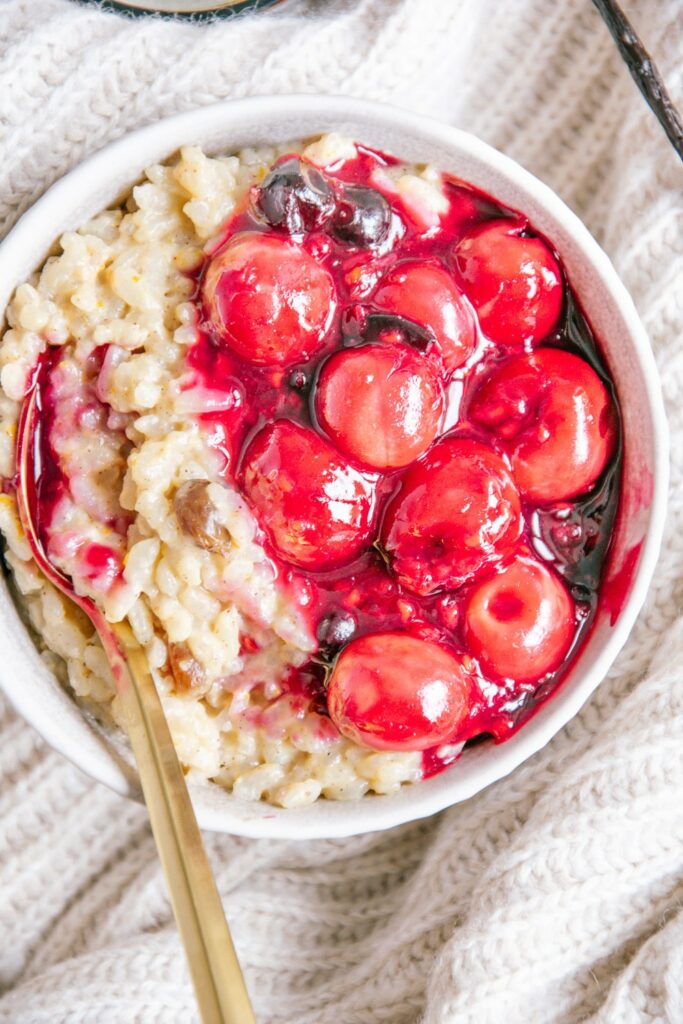 Veganer und zuckerfreier Milchreis mit Kirschkompott, Orangenschale und Rosinen aus der Vogelperspektive fotografiert.