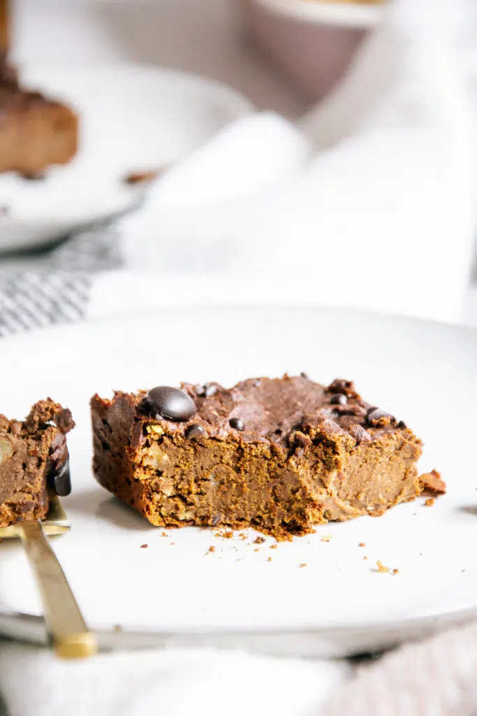 Ein angestochenes Stück veganer und zuckerfreier Protein-Brownie in Frontalansicht und Nahaufnahme.