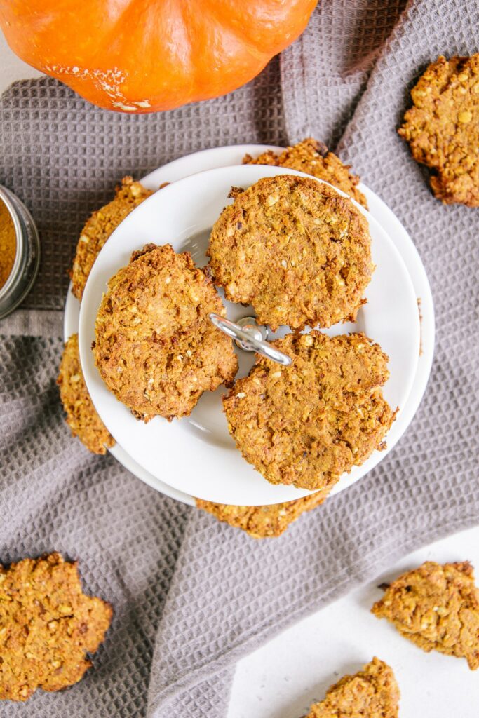 Kleines Etagère mit gesunden veganen Kürbis-Cookies darauf. Aufnahme aus der Vogelperspektive, sodass nur die drei Cookies auf der obersten Ebene ganz abgebildet sind.