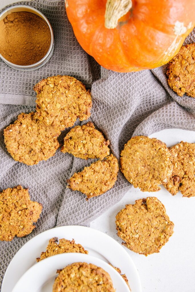 Gesunde vegane Kürbis-Cookies verteilt auf einem grauen Küchentuch. Aufnahme von oben.