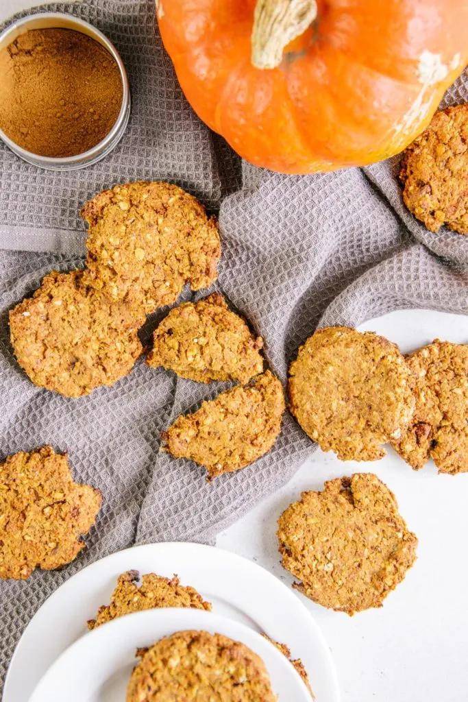 Gesunde vegane Kürbis-Cookies verteilt auf einem grauen Küchentuch. Aufnahme von oben.