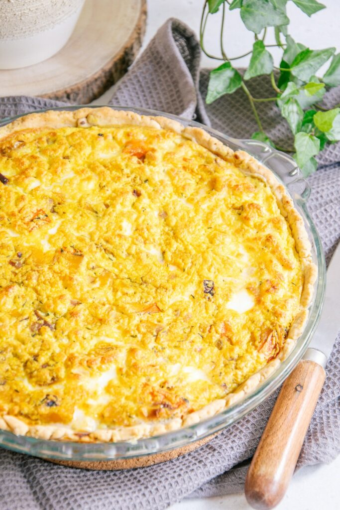 Vegane Kürbis-Quiche in einer Glasform im 45-Grad-Winkel fotografiert. Bild auf der linken Seite angeschnitten