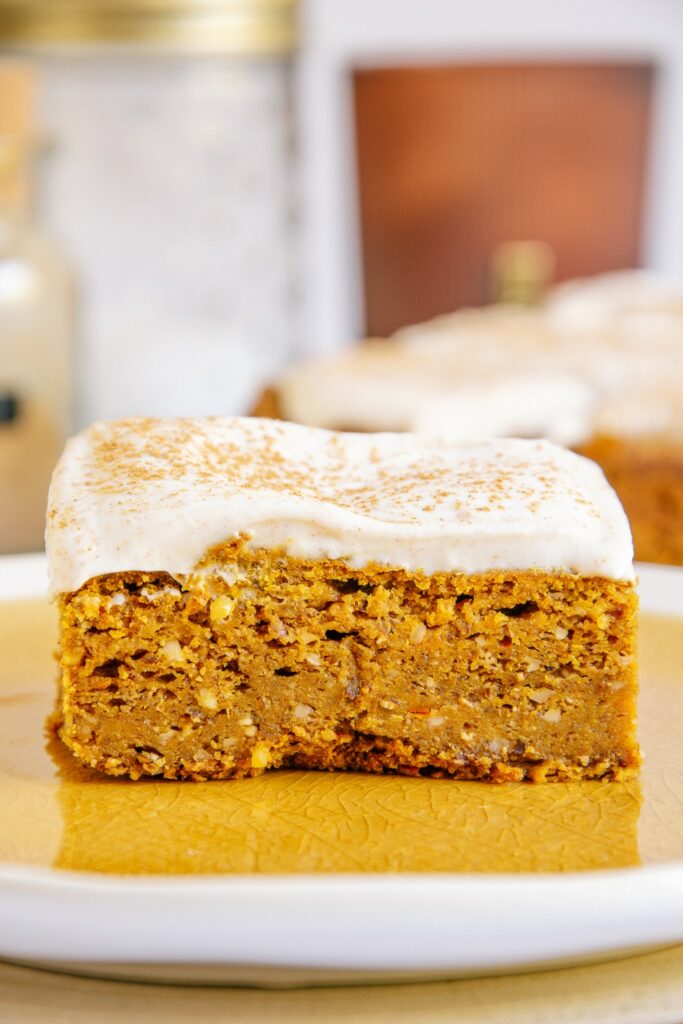 Ein Stück veganer zuckerfreier Kürbiskuchen in der Nahaufnahme auf Augenhöhe. Details von Creme und Teig sind deutlich erkennbar.