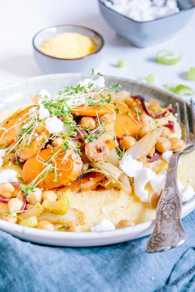 Schmorgemüse mit Cremepolenta im 45-Grad-Winkel auf einem grau-grünen Teller mit einer Retro-Gabel fotografiert.