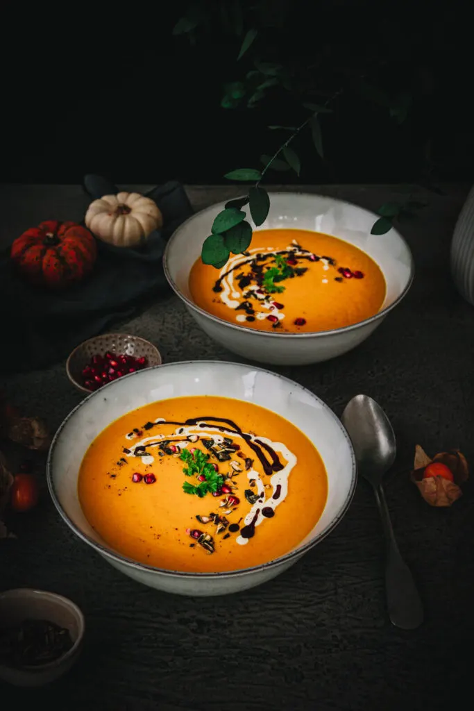 Zwei Teller Kürbissuppe hintereinander in Schrägsicht fotografiert