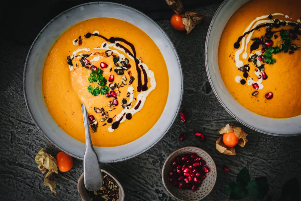Ein großer Löffel in einer Schale mit cremiger veganer Kürbissuppe