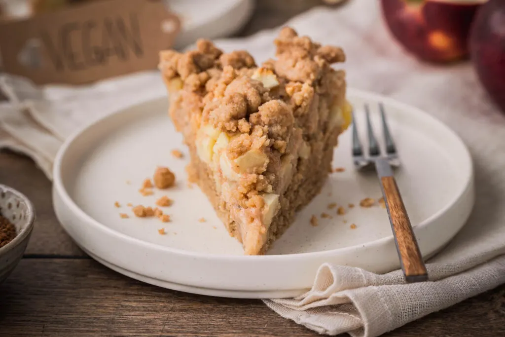 Frontalansicht von einem Stück veganen Streuselkuchen mit Äpfeln