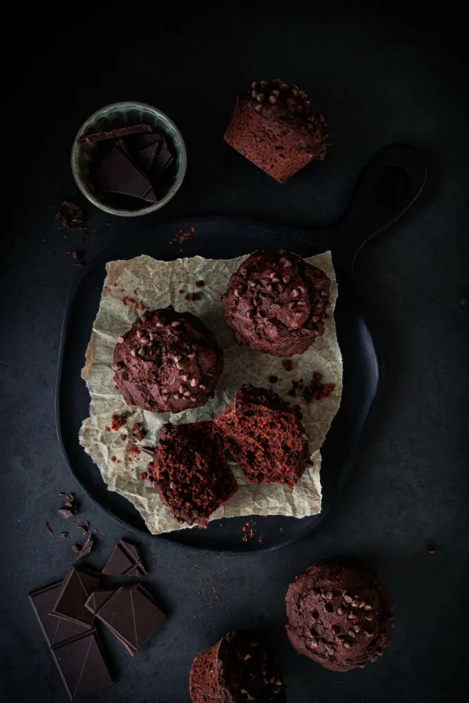 Schoko-Muffins ohne Zucker auf Backpapier und schwarzem Schneidebrett