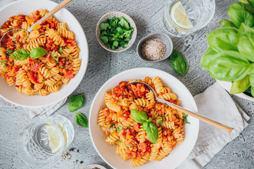 Zwei Teller Pasta mit Gemüsesugo und frischen Kräutern