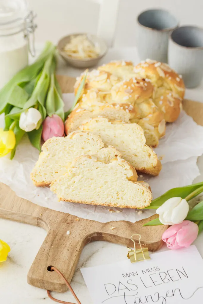 Flaumiger veganer Brioche mit abgeschnittenen Stücken in frühlingshafter Szene mit Tulpen