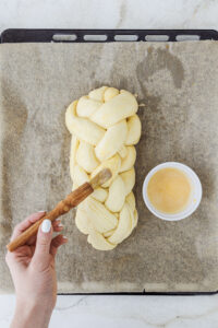 Geflochtener Brioche wird vor dem Backen bestrichen.