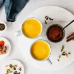 Zwei Tassen goldene Milch und Schale mit Kurkuma-Paste