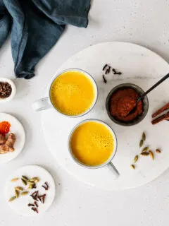 Zwei Tassen goldene Milch und Schale mit Kurkuma-Paste