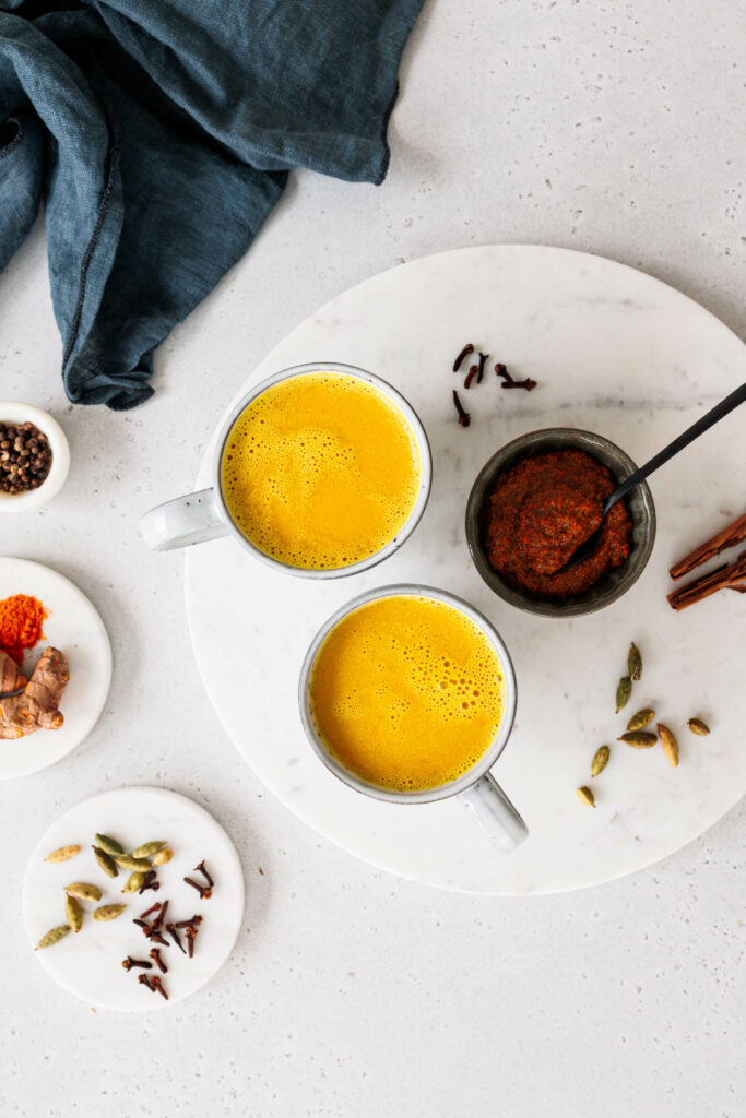 Zwei Tassen goldene Milch und Schale mit Kurkuma-Paste