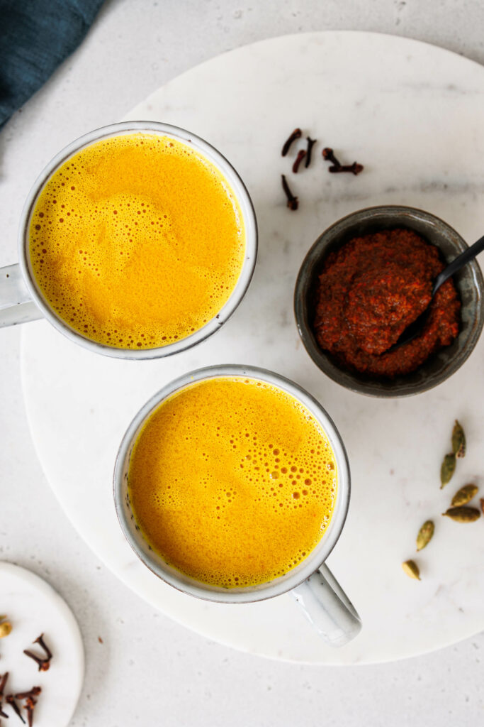 Zwei Tassen goldene Milch und Schale mit Kurkuma-Paste