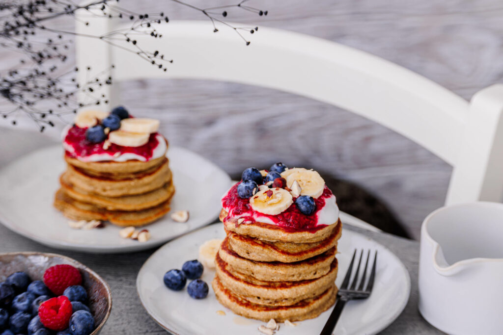 2 Teller mit gestapelten Bananen-Haferflocken-Pancakes