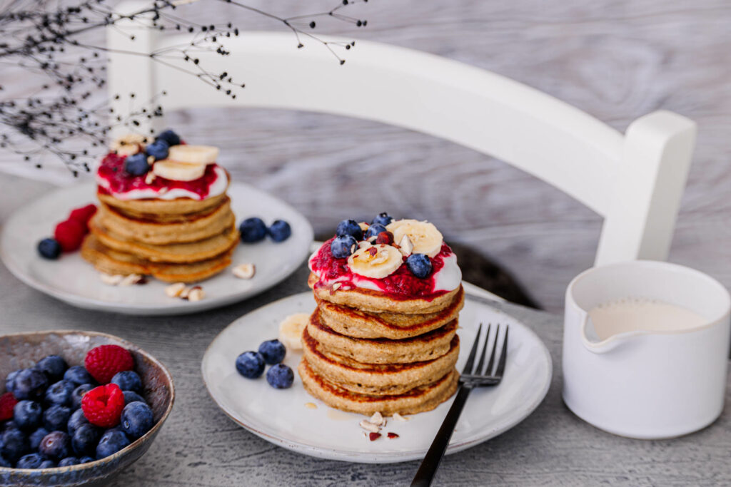 2 Teller mit Pancake-Stapeln auf einem Frühstückstisch