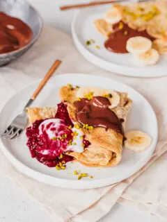 Haferflocken-Pfannkuchen mit Himbeer-Chia-Marmelade, Kokosjoghurt, Schoko-Mandelcreme, Bananenscheiben und gehackten Pistazien