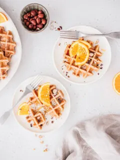 Vegane Vollkornwaffeln mit Orangenscheiben, gehackten Nüssen und Ahornsirup.