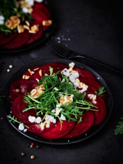 Rote Bete Carpaccio auf schwarzem Teller und schwarzem Untergrund.