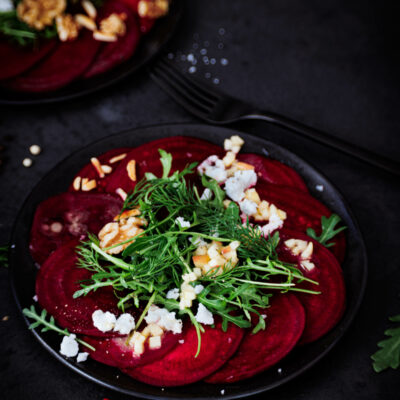 Rote Bete Carpaccio auf schwarzem Teller und schwarzem Untergrund.
