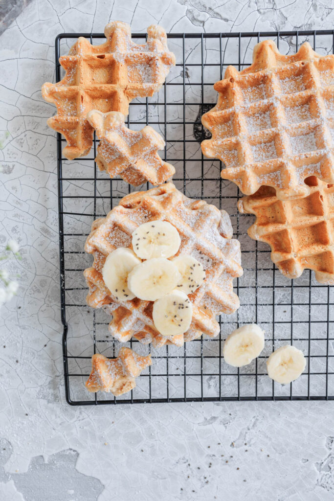 Zuckerfreie Bananenwaffeln auf Kuchengitter, eine davon zerteilt.