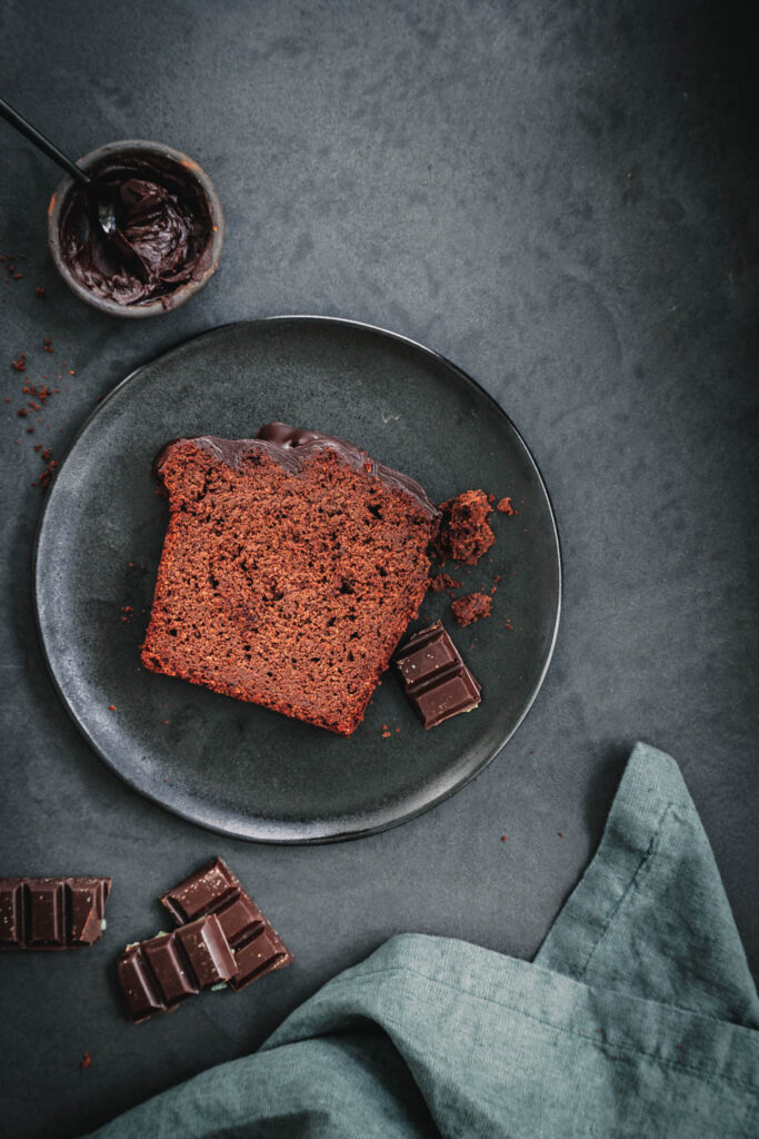 Ein Stück saftiger veganer Schokokuchen mit Dinkelvollkornmehl auf schwarzem Teller.