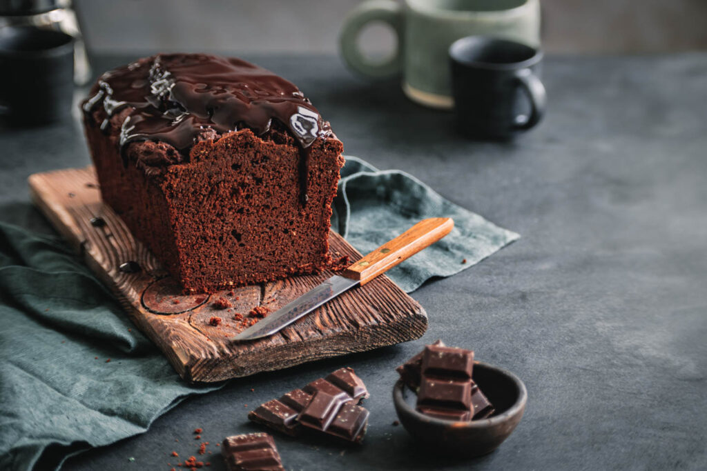 Veganer Schokokuchen ohne Zucker auf Holzbrett und Leinentuch.