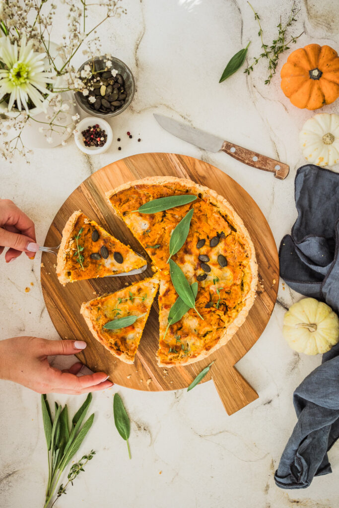 Vegane Kürbis-Quiche auf Holzbrett.