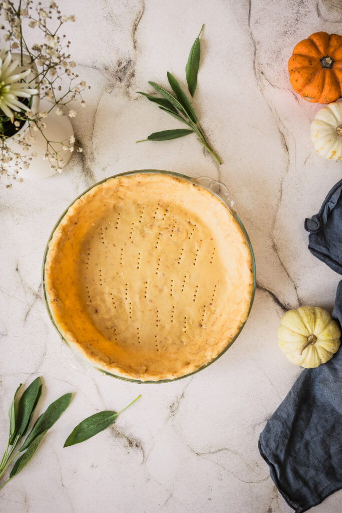 Zubereitung von Kürbis-Quiche: Mürbteig in die Form legen.