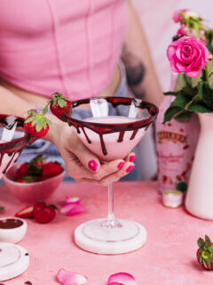 Hand hält ein Glas Erdbeer-Schoko-Martini.