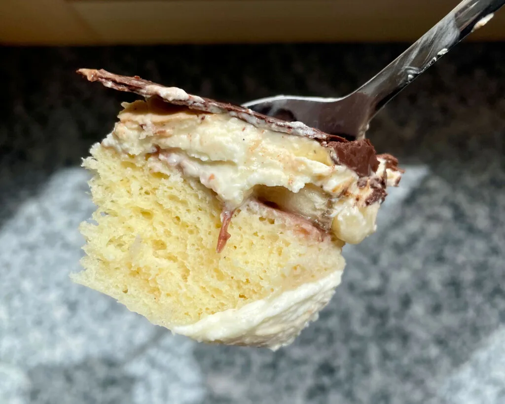 Nahaufnahme von einem Löffel Bananenschnitten-Bowl, sodass die einzelnen Schichten im Detail erkennbar sind.