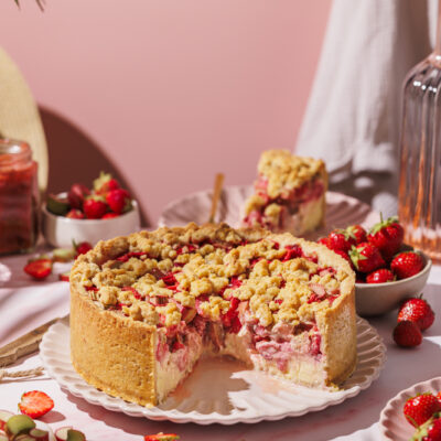 Angeschnittener Erdbeer-Rhabarber-Streuselkuchen mit Vanille-Topfencreme.