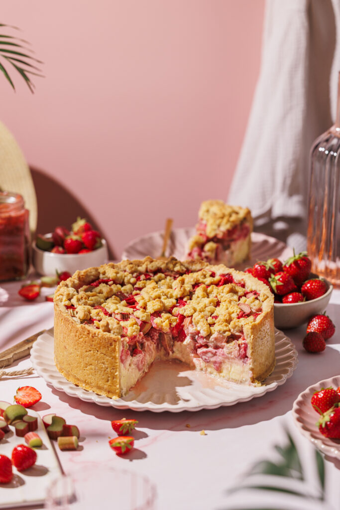 Angeschnittener Erdbeer-Rhabarber-Streuselkuchen mit Vanille-Topfencreme.