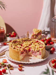 Angeschnittener Erdbeer-Rhabarber-Streuselkuchen mit Vanille-Topfencreme.
