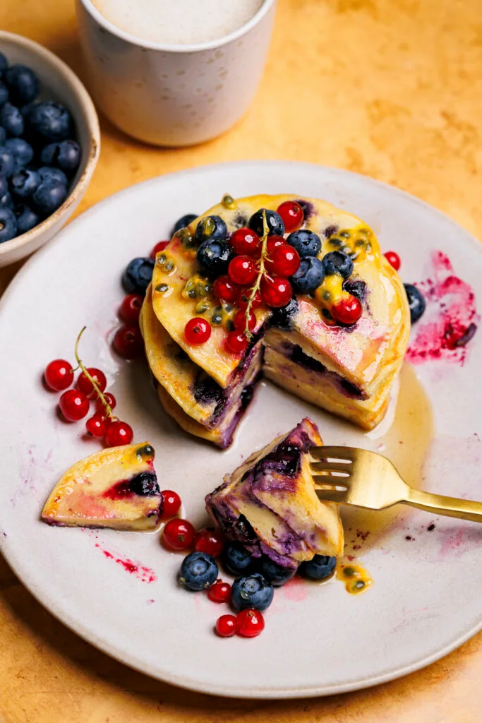 Protein-Blaubeer-Pancakes mit roten Johannisbeeren und Maracuja.
