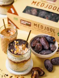 Ein Glas Snickers Overnight Oats mit geknackter Schokoschicht, unter der Dattel-Karamell und die cremigen Oats zu sehen sind.