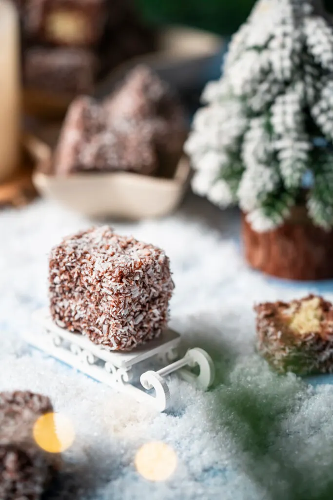 Ein einzelner Kokoswürfel auf einem kleinen Schlitten in einer Winterlandschaft.