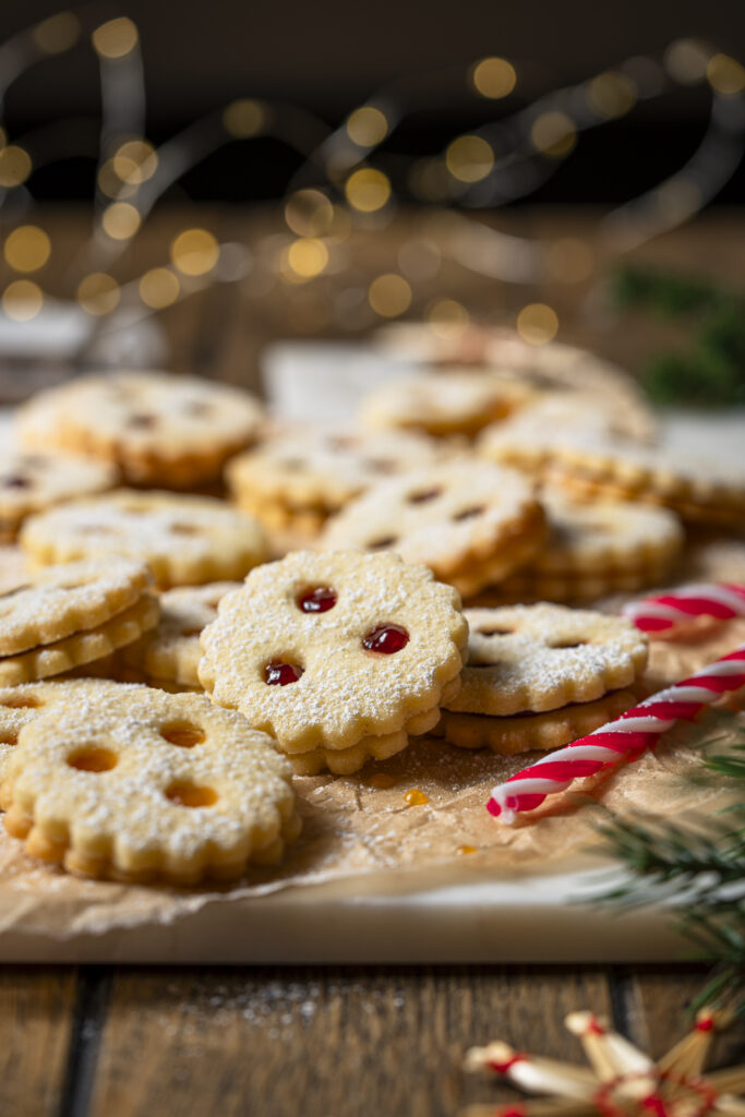 Linzer Kekse in weihnachtlichem Setting mit Zuckerstange und Lichterkette.